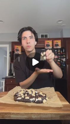 a man is holding out his hand in front of a chocolate cake on a wooden table