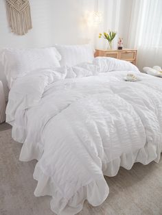 a bed with white comforter and pillows in a room