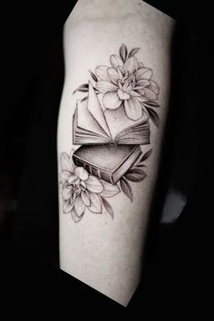 a black and white photo of a book with flowers on its cover - up arm