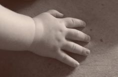 a baby's hand is on the floor next to an apple