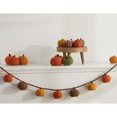 several small pumpkins sitting on top of a shelf next to a string of yarn