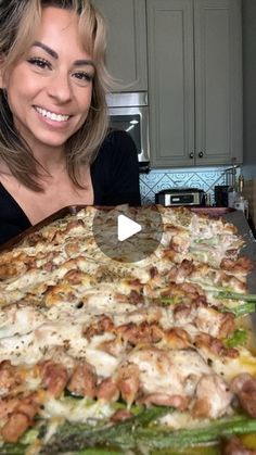 a woman is smiling while looking at a large pizza