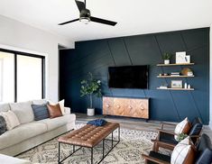 a living room filled with furniture and a flat screen tv mounted on a wall above a fireplace