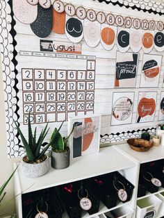 a wall with calendars on it and plants in pots next to the shelf filled with cards