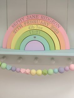 there is a rainbow shaped sign on the shelf with bunting garlands in front of it