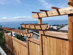 a wooden fence on the side of a building with water in the distance behind it