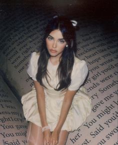 a woman sitting on top of a book with her legs crossed