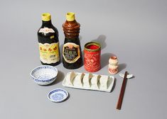 an assortment of condiments and sauces are arranged on a gray surface with chopsticks