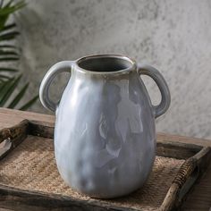 a white vase sitting on top of a wooden tray