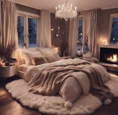 a large bed sitting in a bedroom under a chandelier next to a fire place