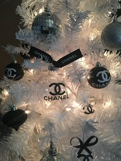 a chanel christmas tree with ornaments and lights on it's white artificial branches