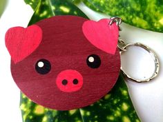 a wooden keychain with a pig face painted on it's front and side