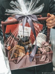 a person holding a bag full of wine and chocolates in it's hands