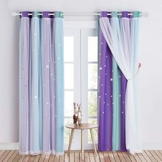 the curtains in this room are blue and purple with white stars on them, while the floor is wooden planks