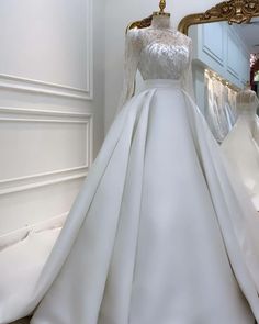 a wedding dress on display in front of a mirror