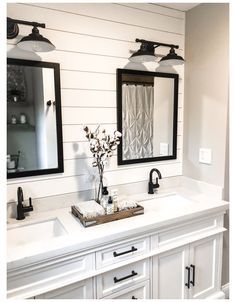 a bathroom with two sinks, mirrors and lights on the wall above them is shown