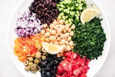 a white bowl filled with different types of vegetables and olives on top of each other