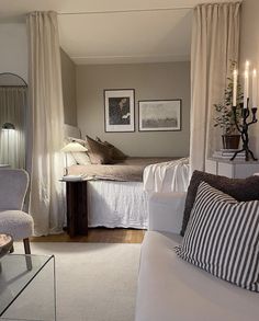 a living room filled with furniture next to a bed and a window covered in curtains