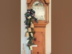 an old grandfather clock decorated for christmas with garland and bells on the front, along with other decorations