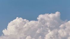 an airplane is flying high in the sky above some white fluffy clouds and blue skies