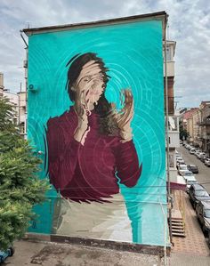 a painting on the side of a building with a woman holding her hands up to her face