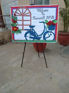 a welcome sign with a bicycle on it in front of a potted palm tree