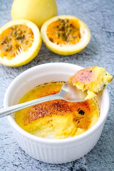 a spoon in a bowl filled with food next to two halves of an orange on the table