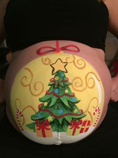 a pregnant woman's belly decorated with christmas trees and bows, painted in bright colors