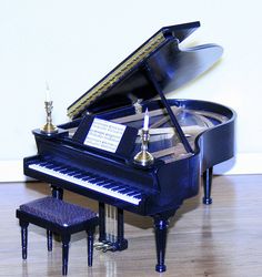 a miniature piano sitting on top of a hard wood floor next to a small stool