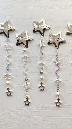 five star charms hanging from the side of a white wall, each with different colors and shapes