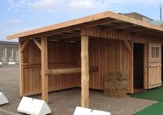 a wooden shed with hay bales in the yard