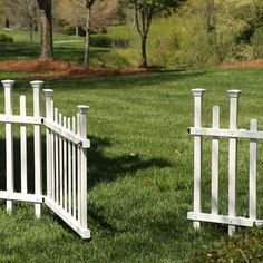 two white picket fences sitting in the grass