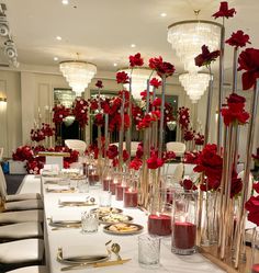 a long table with red flowers and candles on it