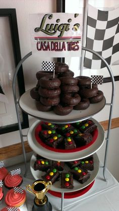 three tiered trays filled with chocolate covered donuts and cupcakes on a table