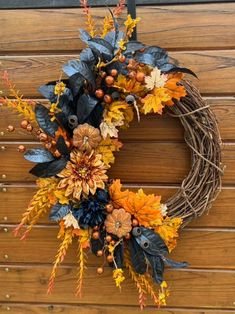 a wreath with autumn leaves and berries hanging on a wooden wall next to a door