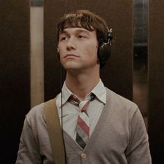 a man with headphones on standing next to an elevator