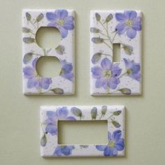 three white and blue flowers are placed in the shape of two light switchplates