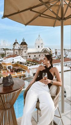 a woman sitting on top of a chair next to a wine glass in her hand