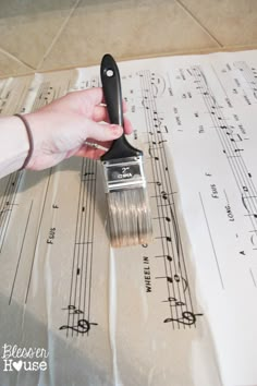 a person holding a brush over sheet music