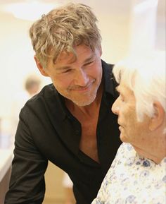 an older woman talking to a man in a black shirt