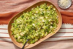 a bowl filled with chopped green vegetables on top of a table next to a spoon