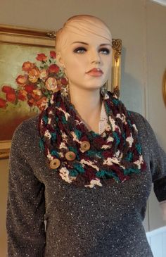 a mannequin wearing a gray sweater and multicolored crocheted scarf