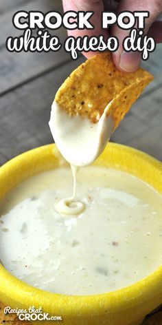 a hand holding a tortilla chip over a bowl of white quesadilla dip