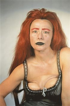 a woman with red hair and black makeup is posing for a photo in front of a white background