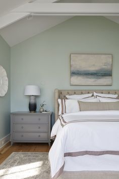 a bed sitting in a bedroom next to a dresser with a lamp on top of it