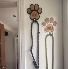 two dog leashes are hanging on the wall with their name and paw prints attached to them