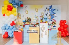 a room filled with balloons and decorations on the wall next to a cake table in front of a sonic birthday backdrop