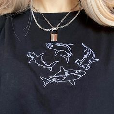 a woman with blonde hair wearing a black t - shirt and silver necklace that has dolphins on it