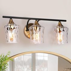 three light bathroom fixture with clear glass shades and gold trimmings on the wall