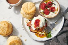 a plate topped with eggs and bacon next to biscuits on top of a table